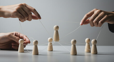 Two hands manipulating wooden figures with strings against a gray background in a studio setting