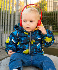 A young child wearing headphones and a blue jacket