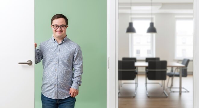 Man with down syndrome in patterned shirt glasses standing office doorway conference room background. Professional employee workplace inclusion diversity. Disability employment 