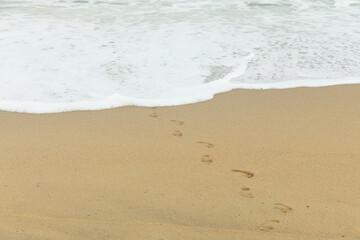 Footprints and wave in the sand. Horizontal.