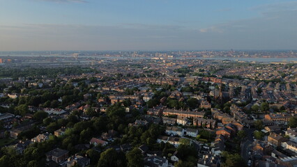 Aerial view of UK town in low sunlight depicting housing buildings near body of water.