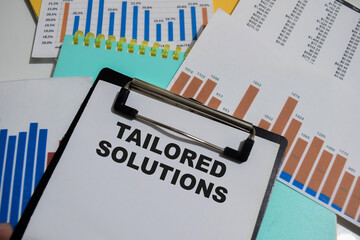 Concept of Tailored solutions write on paperwork isolated on Wooden Table.