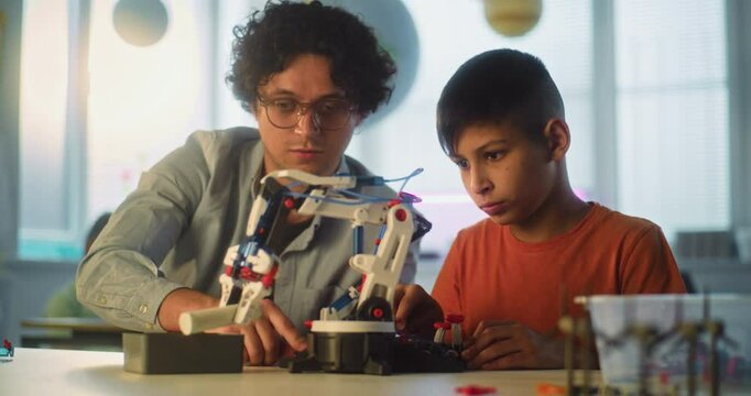 Interactive Learning and Creative STEM Education in Primary School: Talented Boy Studying Robotic Arm Model with Teacher. Young School Student During Science and Technology Lesson in Modern Classroom.