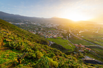 View from the Mirador de Humboldt lookout of the Orotava Valley towns of Puerto de la Cruz, La Orotava and Los Realejos, with Mt Teide volcano in the distance, Tenerife Island, Spain at golden hour.