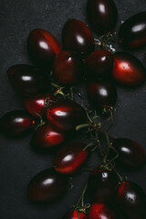 Fresh organic black tomatoes on dark background, ready for healthy food preparation in the kitchen