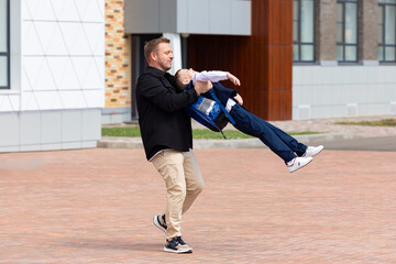 Happy father spinning his son around outside after school lessons while playing and spending time...