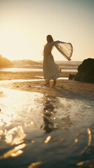 A girl in a sari dances against the backdrop of the ocean at sunset. Meditation.  Yoga. Soft focus