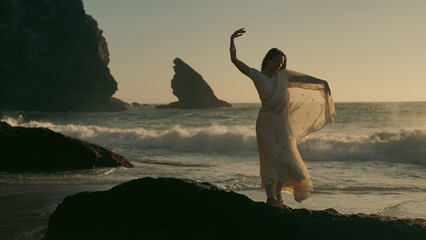 A girl in a sari dances against the backdrop of the ocean at sunset. Meditation.  Yoga. Soft focus