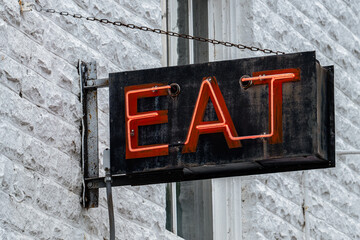 Vintage Neon “EAT” Sign on Weathered Brick Wall