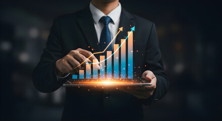 A business professional holding a digital tablet with a glowing 3D bar chart and upward arrows emerging from the screen, symbolizing business growth and financial success