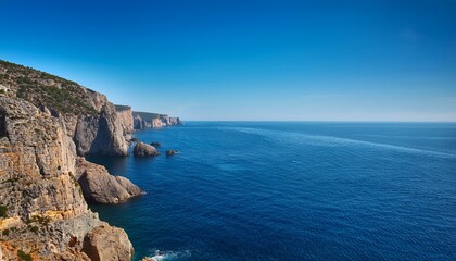 Fototapeta premium a rugged coastline with steep cliffs overlooks a calm deep blue sea under a clear sky