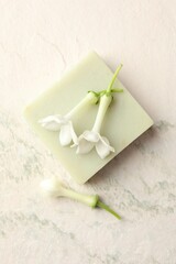 Bar of soap and jasmine flowers on light table, flat lay