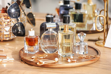 Bottles of different perfumes and accessories on wooden table