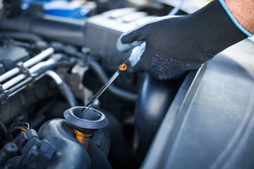 Worker checking motor oil level in car with dipstick, closeup