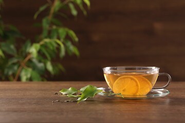 Cup of tasty green tea with lemon on wooden table, space for text