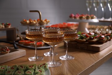 Buffet menu. Glasses of sparkling wine and tasty appetizers on table, closeup