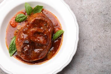 Traditional ossobuco dish with beef steak and sauce on grey table, top view. Space for text