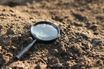 Magnifying glass on dry soil in field