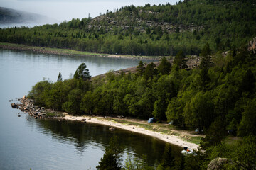 Fototapeta premium Aerial View of Sandy Beach with Tents on Forest Lake Shore