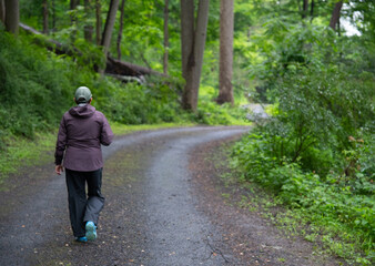 A woman walking alone on a forest road enjoying the serenity and solitude of being in nature