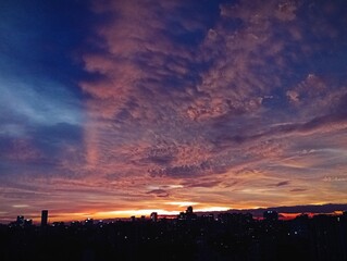 Sunset skyline view over the city with glowing clouds and urban lights.