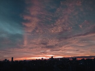 Sunset skyline view over the city with glowing clouds and urban lights.