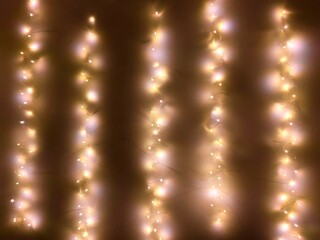 delicate garland made warm white lights hangs elegantly indoors, enhancing ambiance with soft glow. perfect for decoration during festive occasions or intimate gatherings. close up.