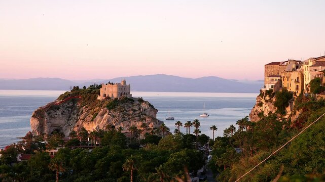 Pink sunset over the Tyrrhenian Sea with the Sanctuary of Santa Maria dell Isola and the town of Tropea, Calabria, Italy