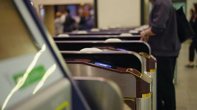Crowd of People walking pass ticket gate in subway station in rush hour morning. Passenger using card and smartphone mobile app making payment for public transportation at train station in the city.