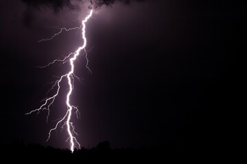 Dramatic Lightning Bolt Strikes Against Dark Stormy Sky in Night Landscape Scene