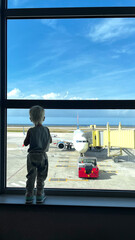 Close up of little blond boy standing back to camera and is curiously watching out of big window in...