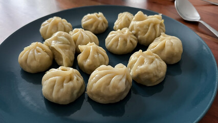 Plate full of traditional steamed Nepali dumpling Momo  filled with chicken, meat, seafood or vegetables. Homemade exotic food, inspiration through traveling 