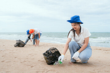 Volunteers clean the beach while collecting plastic waste on a cloudy day near the shoreline