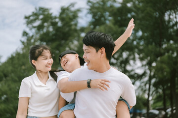 Obraz premium Family enjoying a sunny day outdoors with laughter and smiles in a green park