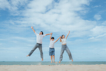Obraz premium Joyful family celebrates at the beach with jumps under the sunny sky during summer afternoon