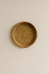 A round rattan wall piece hangs on a soft beige wall—celebrating stillness, culture, and the quiet beauty of handmade tradition in a minimalist space.