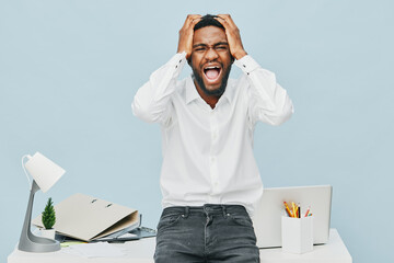 Frustrated young African-American man expressing stress frustration in office environment, holding...