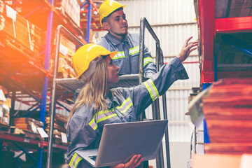 Two logistic factory  workers, man and woman in a warehouse, check stocks and reviewing data on a...