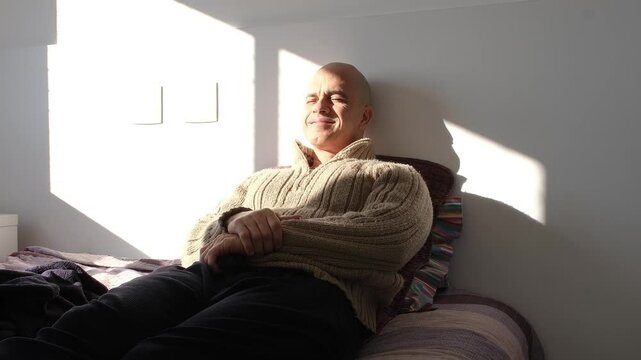 49 year old Brazilian man waking up from a nap in bed under the sunlight.
