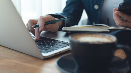 Business woman working on laptop computer with notebook for business plan, remote work from cafe....