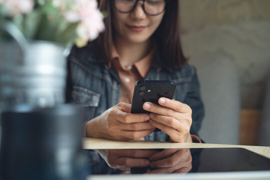 Close up, young asian woman using mobile phone for online shopping, digital banking and social networking via mobile app at coffee shop, surfing the internet, online messaging, people lifestyle