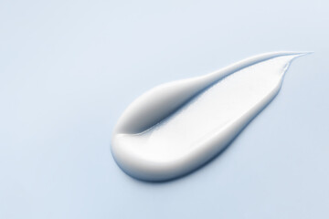White cosmetic cream swatch, lotion smear on blue background. Creamy skincare product texture