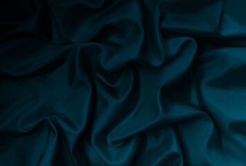 Dark blue shadowes crumpled satin sabric. Satin background for design. Azure, teal, navy, denim, midnight, cobalt colorful background. Wavy drapery folds. Curve. Twisted cloth. Smooth shiny drape. 