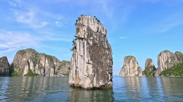 Close-up of majestic limestone islands rise from the emerald waters of Ha Long Bay, Vietnam, under a bright blue sky.

