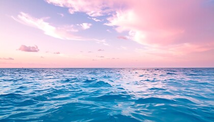 Obraz premium Ocean waves at sunset under pink clouds.