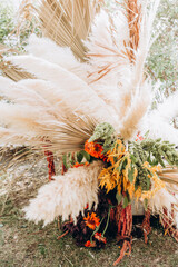 Elegant boho wedding arrangement with pampas grass, dried palm leaves, orange flowers, and candles...