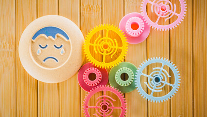 The toy, a crying baby surrounded by colorful gears, symbolizes the many complex factors...