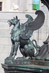 
a bronze-colored statue of a vulture with wings and an open mouth, possibly part of a larger...