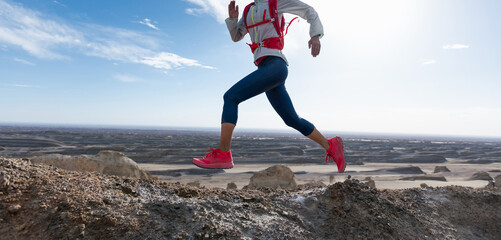 Woman trail runner cross country running on sand desert mountain top