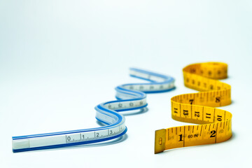 Flexible ruler and tape measure are lying on a white background, illustrating measurement concepts